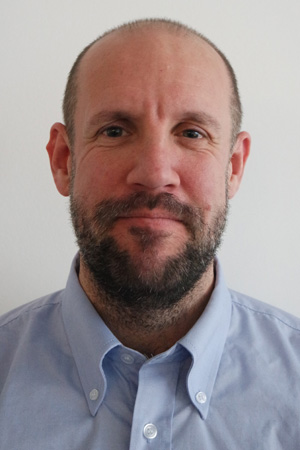 Tim Rimmer - Compliance Manager. A Man with a beard wearing a shirt/